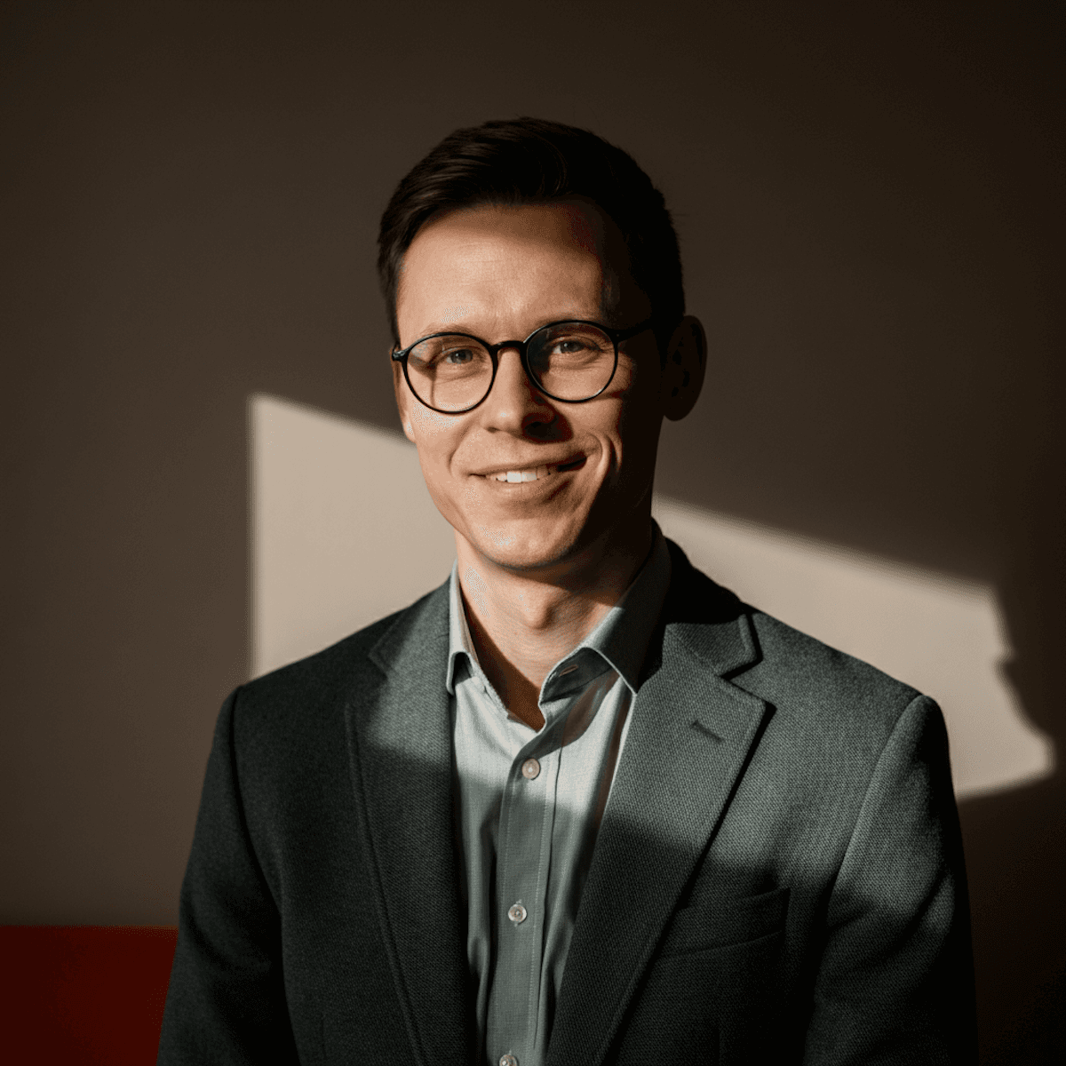 a smiling man in a suit with sunlight